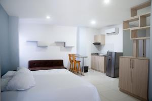 巴兰基亚Apartaestudios lagos的一间带白色床的卧室和一间厨房