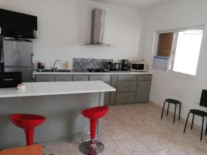 明德卢Casa Yô的厨房里设有柜台和红色凳子