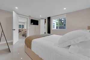 好莱坞Casa Copal: Relaxing Beach House的白色卧室设有一张大床和电视。