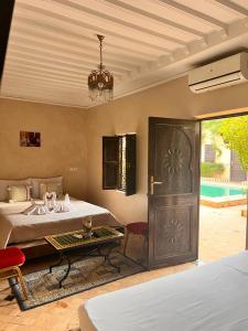 马拉喀什Riad Rime Garden Marrakech的一间卧室设有两张床、一张桌子和一扇门