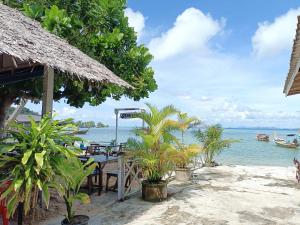 班柯木柯木海景简易别墅旅馆的海滩上设有桌椅,大海上设有沙滩