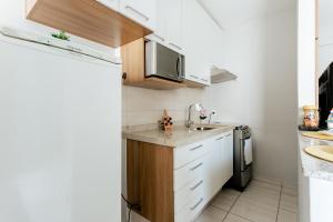 波苏斯-迪卡尔达斯Super bem localizado, no centro, com varanda!的一间带水槽和冰箱的小厨房