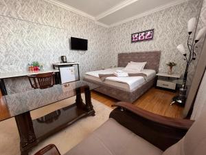 努库斯MASSAGET HOTEL的一间卧室配有一张床、一张桌子和一张沙发