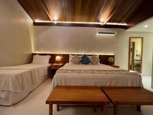费尔南多 - 迪诺罗尼亚Pousada Naonda的一间卧室设有两张床和木制天花板