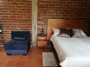 巴尼奥斯Casa y Flores的一间卧室配有一张床和一张蓝色椅子