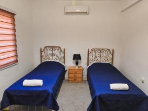乌姆盖斯Beit Philodemus的一间卧室配有两张床和一个带灯的床头柜