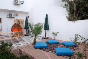 达哈布Tranquilo Boutique Hostel - Dahab的一个带蓝色靠垫、桌子和雨伞的庭院