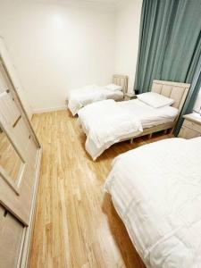 利雅德2 Bedroom Apartment 2BB的铺有木地板的客房内的三张床