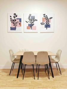 利雅德2 Bedroom Apartment 2BB的餐桌、四把椅子和墙上的绘画