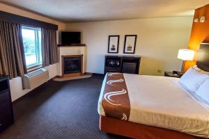 AtchisonQuality Inn Atchison的酒店客房配有一张床和一个壁炉。
