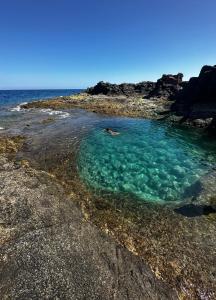 科斯塔德安提瓜Apartamento BLUE OCEAN Complex Amaya Fuerteventura的岩石海滩上的清澈海水