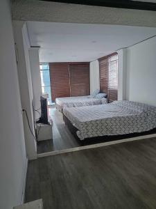 波哥大habitaciones disponibles en una casa en el norte de la ciudad, a 5 minutos del portal norte的一间卧室配有两张床和电视。