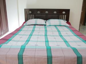 达卡Golpata Bed & Breakfast的一张带两个枕头和毯子的床