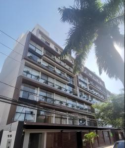 圣克鲁斯Lujoso depto. en Equipetrol的公寓大楼前方有棕榈树