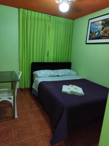 齐克拉约HOTEL REY DE ORO的一间卧室配有一张带桌子和绿色窗帘的床