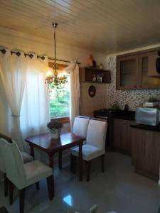 格拉玛多chalé do Riacho的一间带木桌和白色椅子的厨房以及一间用餐室