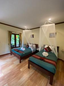 考索Khao Sok River & Jungle Bungalow的铺有木地板的客房内的两张床