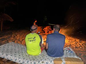 基林多尼Juani beach bungalows的两个坐在海滩上看火的人