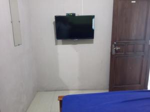 LaweanOYO 93012 Griya Kencana Asri Syariah的一间墙上配有电视的房间和一张床