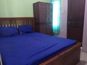 LaweanOYO 93012 Griya Kencana Asri Syariah的一间卧室配有一张蓝色的床和木架