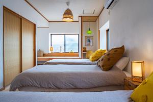 直岛町Naoshima Juju Art House　直島ジュジュアートハウス的一间卧室设有两张床和窗户。
