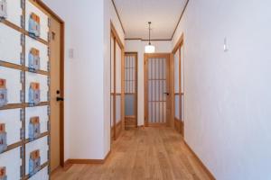 直岛町Naoshima Juju Art House　直島ジュジュアートハウス的走廊铺有木地板,设有白色的墙壁和木门