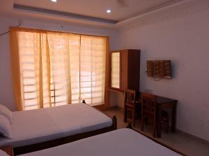 特里凡得琅Somatheertham Ayurvedic Resort的一间卧室设有两张床、一张桌子和一个窗口。