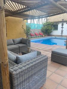 奇克拉纳－德拉弗龙特拉Casa Rural Los Pepe Sancti Petri的一个带柳条家具的庭院和一个游泳池