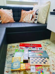 马尼拉1 Br CONDO Vine Residences Quezon City with POOL NETFLIX WIFI VIDEOKE BOARD GAMES的坐在沙发前的地板上堆的书