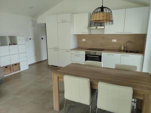 科济纳Gaja & Sara Apartments的厨房配有木桌和白色橱柜。