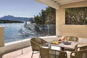 巴哈撒丁岛7Pines Resort Sardinia - A Destination By Hyatt的阳台配有桌椅,享有水景