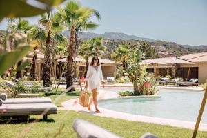 巴哈撒丁岛7Pines Resort Sardinia - A Destination By Hyatt的一位女士在度假村的游泳池边走