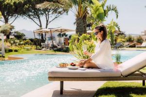 巴哈撒丁岛7Pines Resort Sardinia - A Destination By Hyatt的坐在游泳池旁长凳上的女人