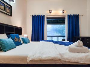 莫尔吉姆Beach Villa Morjim的一间卧室配有一张带蓝色窗帘的大床