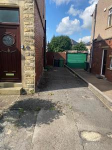 哈德斯菲尔德Huddersfield 2 bedroom house的一条带棕色门和绿色车库的小巷