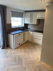 哈德斯菲尔德Huddersfield 2 bedroom house的厨房铺有木地板,配有白色橱柜。