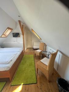 尼尔堡巴卡豪森宾馆的一间卧室配有一张床和两把椅子,并铺有绿色地毯。