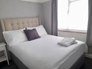 曼彻斯特Bright 4-Bed house 15 min to Manchester Centre的一张带两个枕头和窗户的大型白色床