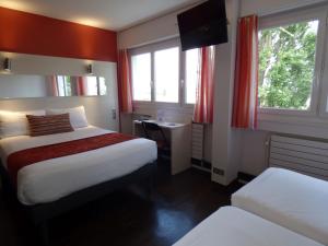 马孔Cit'Hotel Escatel的酒店客房带两张床和两个窗户