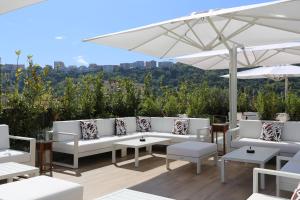 那不勒斯LHP Napoli Palace & SPA的庭院配有白色的沙发、桌子和雨伞。