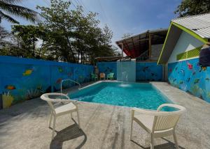 托尔图格罗Hotel El Icaco Tortuguero的蓝色墙壁前的游泳池,配有两把椅子