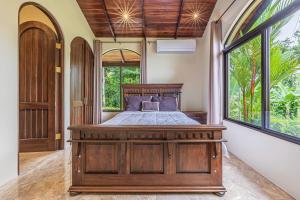 乌维塔Las Palomas Villas Of Uvita的一间卧室设有一张木床和一个大窗户。
