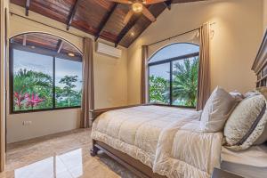 乌维塔Las Palomas Villas Of Uvita的一间卧室设有一张床和两个大窗户