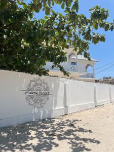 帕杰Mauwa House的白色的栅栏,上面有读库伦房子的标志