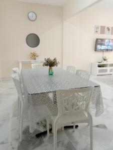 Kampong Tanah MerahRafflesia Two Bedroom Pool View的餐桌,配有白色椅子和花瓶