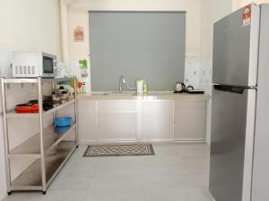 Kampong Tanah MerahRafflesia Two Bedroom Pool View的厨房配有白色橱柜和不锈钢冰箱