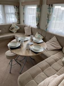 塞尔西Emeralds caravan lettings的客厅配有桌子和沙发