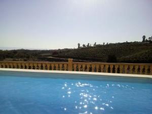 贝莱斯Casa rural CAÑADA PAEZ的一个带栅栏和山丘的蓝色游泳池