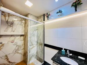 维拉维尔哈Praia Dourada的一间带玻璃淋浴和水槽的浴室