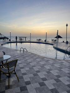 Ḩumrفندق حدائق فرسان الفندقية的海滩旁的游泳池,有人在散步